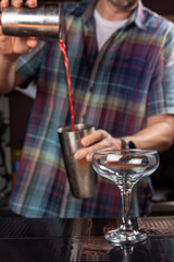 Bartender is making cocktail at bar counter, closeup.