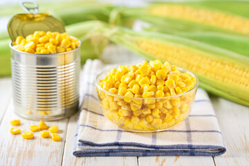Canned food maize in a clear glass bowl on a white kitchen table, selective focus.