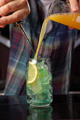 Barman pouring a drink from a bottle into a glass with ice
