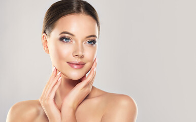 Beautiful Young Woman with Clean Fresh Skin touch own face . Facial treatment . Cosmetology , beauty and spa .