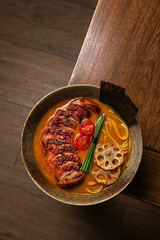 Ramen noodle soup with pork in bowl on wooden table.