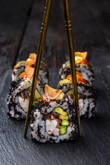 Sushi roll with salmon, avocado and cucumber on a black background