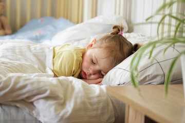 Peaceful adorable baby sleeping on a bed at home. Slumbering little child. Two years old girl sleeps peaceful at domestic room interior background. Serene dream. Cute face close up. Deep kid slumber