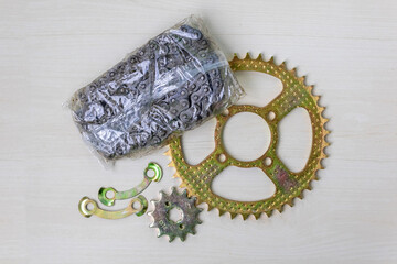New motorcycle chain sprocket set, top view on wooden surface. Essential bike maintenance parts.