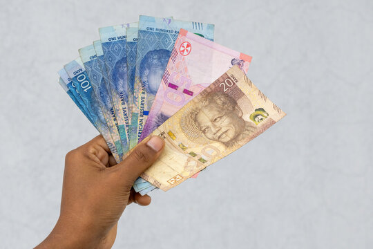 South African Rand currency in female hand, including 20, 50, and 100 Rand notes. Financial concept of wealth and economy.