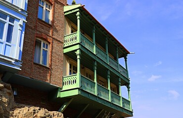 Traditional Georgian wooden house with large balconies on the edge of a rocky cliff in the old town...