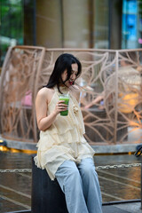 Elegant Woman Holding Matcha Green Tea with Wind Blown Hair Outdoors