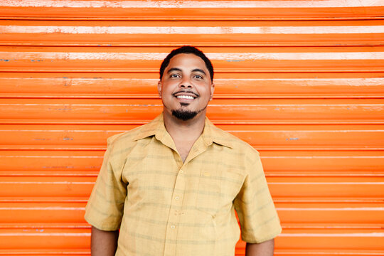Smiling dominican man posing in front of orange wall