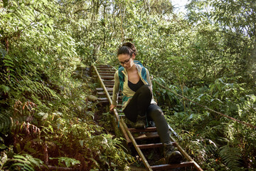 Woman descending rustic stairs along a jungle hike