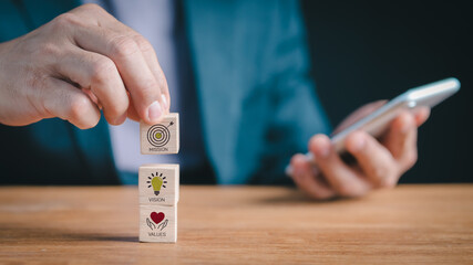 Defining corporate identity: Person assembling blocks depicting mission statement, future vision, and fundamental values, crucial for business success and brand integrity.