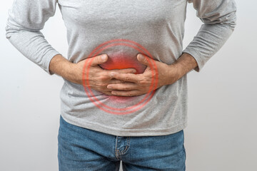 Mature man clutching his stomach. Symptoms of inflammation and pain in the intestines, liver, and stomach in an adult man.
