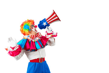 Funny clown shouting with loudspeaker. Entertainer Joker in colorful suit and wig. Trickster, jester, pantomime, mime, whiteface makeup. Professional actor at event, kids party, circus.