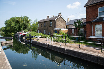 Enfield Lock on a sunny day, showcasing the historic canal lock gates, calm waters, and surrounding...