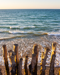 Wooden breakwaters on beach at sunset, Saint-Malo, Brittany, France – vertical photo
