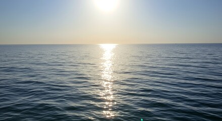 Obraz premium Serene ocean view reflecting sunlight under a clear blue sky creates tranquility