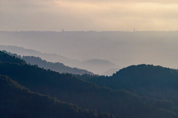 The soft light of dawn illuminates the forested mountain ranges