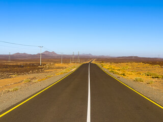 A road stretches to the horizon through the desert of Saudi Arabia.