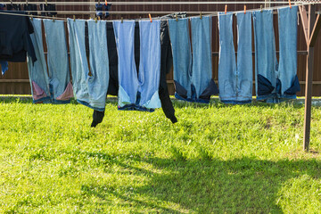 Hanging jeans and clothing drying under the sun on a spring day in a backyard