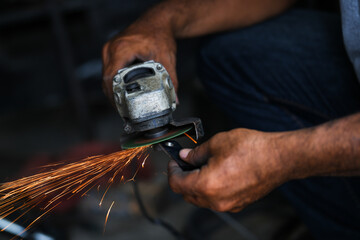 Grinding a steel plate with an electric hand wheel at a factory