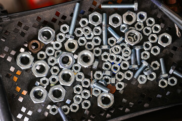 Closeup of nuts and bolts on the metal tray in factory