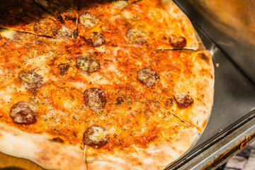 Fresh pepperoni pizza with golden crust and melted cheese displayed behind glass. Fast food, street...