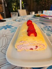 A delectable strawberry cream roll cake, generously topped with fresh strawberries and dusted with...
