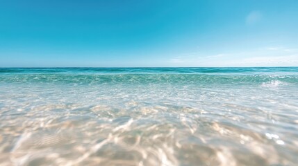 A tranquil view of crystal clear ocean water gently lapping at the shore under a brilliant blue sky, evoking feelings of peace, serenity, and the beauty of nature's seascape.