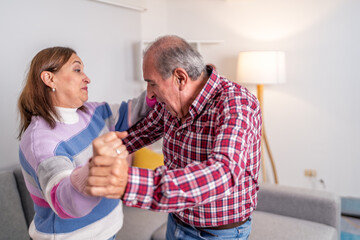 Senior couple playfully arguing and dancing at home
