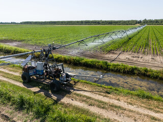 Autonomous machine is moving watering pivot along irrigation canal