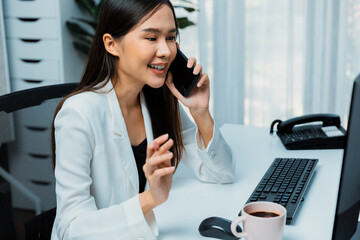 Working young Asian businesswoman calling to customer to present marketing online strategy...