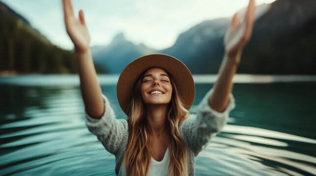 This uplifting image depicts a joyful woman standing in a serene lake, arms outstretched, celebrating life and the beauty of nature against a stunning mountainous backdrop.