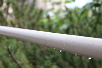 close-up macro raindrops dangling from gray (grey) steel railing