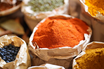 Colorful selection of dried herbs, spices, and natural ingredients in paper bags on rustic market...
