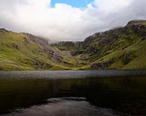 A mystical landscape unfolds, a still lake reflecting misty mountains, wildness and tranquility combined.