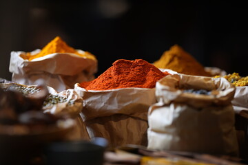 Colorful selection of dried herbs, spices, and natural ingredients in paper bags on rustic market...