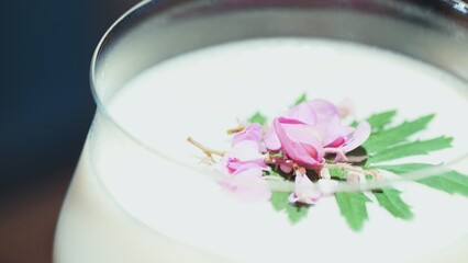 Closeup mixed passion fruit and sweet liquor cocktail decorated adding pink flower on top, making special creative drink menu list for advertisement in focusing alcohol refreshing showcase. Vinosity.