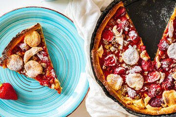 Rhubarb and strawberry tart in a baking tray and a slice of dessert on a turquoise plate. A...