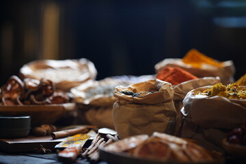 Colorful selection of dried herbs, spices, and natural ingredients in paper bags on rustic market...
