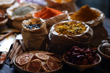 Colorful selection of dried herbs, spices, and natural ingredients in paper bags on rustic market...