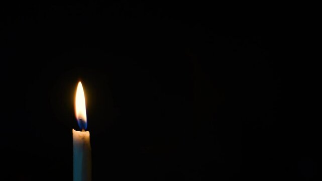burning candle on black background in one side of the frame