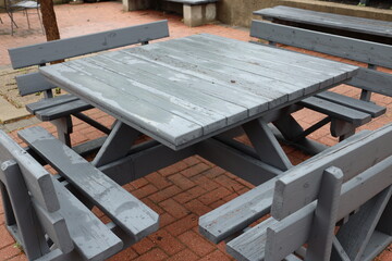 large outdoor wooden table with benches on paved patio still wet from recent rain