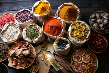 Colorful selection of dried herbs, spices, and natural ingredients in paper bags on rustic market...