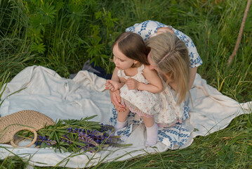 A mother and her little daughter embrace during a picnic in nature on a sunny day