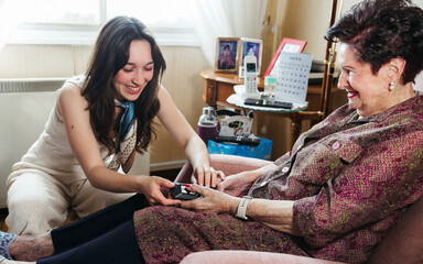 Granddaughter helping senior grandmother with recliner chair control at home