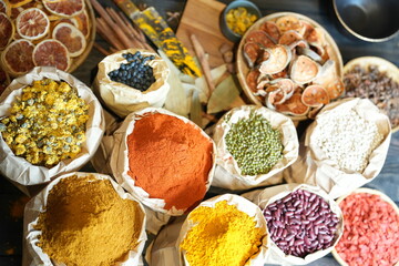 Colorful selection of dried herbs, spices, and natural ingredients in paper bags on rustic market...