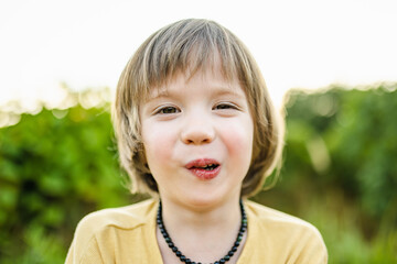 Adorable little boy having fun outdoors on sunny summer day. Kid running outdoors. Child exploring...
