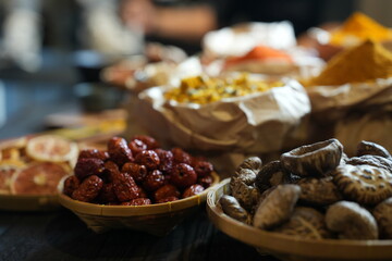 Colorful selection of dried herbs, spices, and natural ingredients in paper bags on rustic market...
