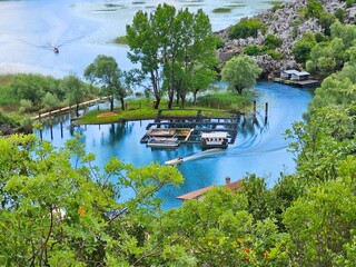 Small motorboats create wakes as they navigate the serene blue waters of skadar lake, a stunning...