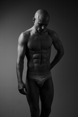 Fototapeta premium Black and white portrait of a muscular man, showcasing strength and expression, conveying emotion through body language and posture in a minimalistic style.