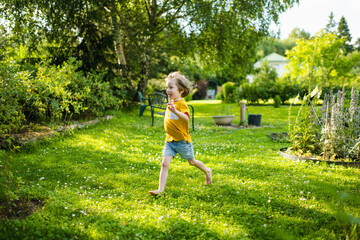 Adorable little boy having fun outdoors on sunny summer day. Kid running outdoors. Child exploring nature. Summer activities for kids.
